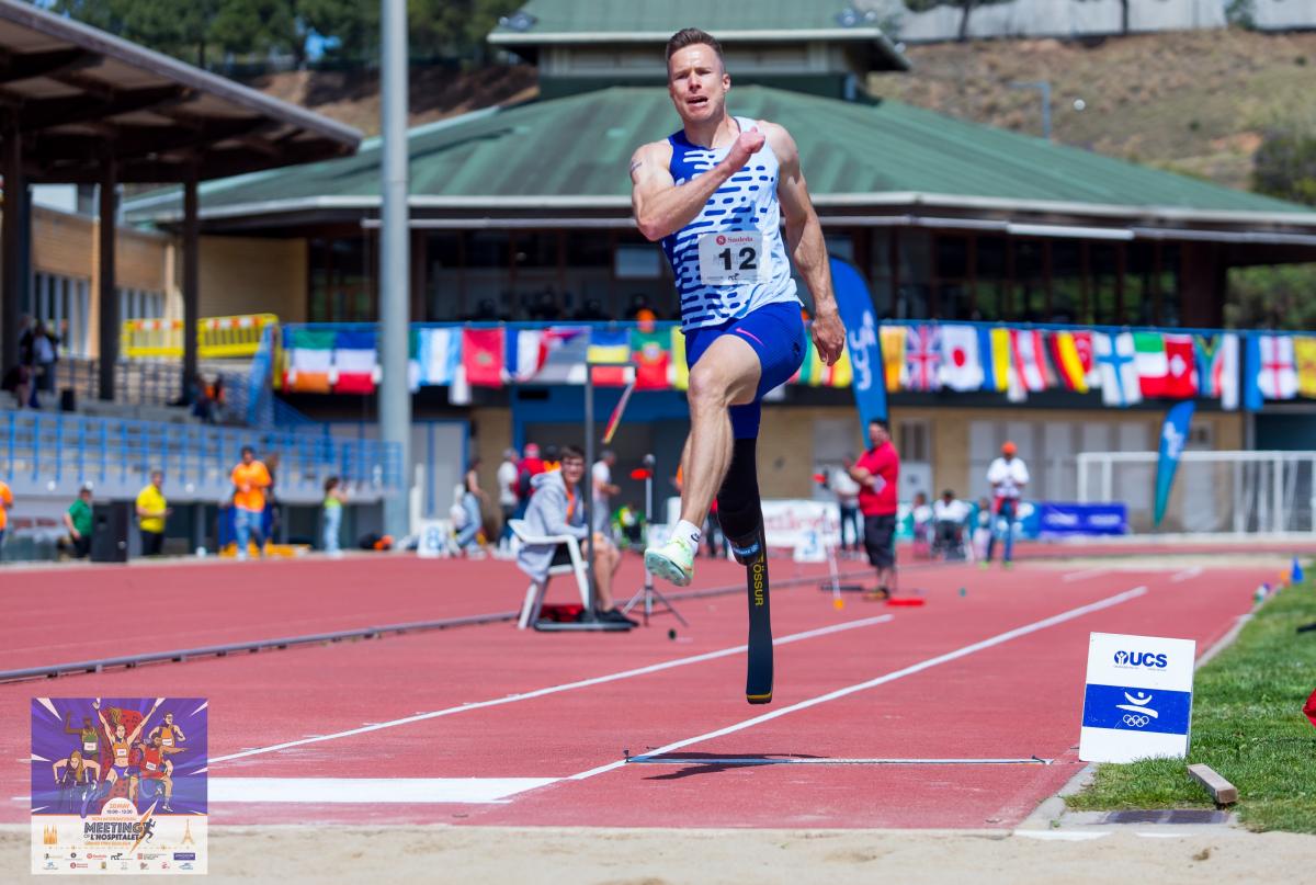 A male long jumper jumping with a prosthetic right leg