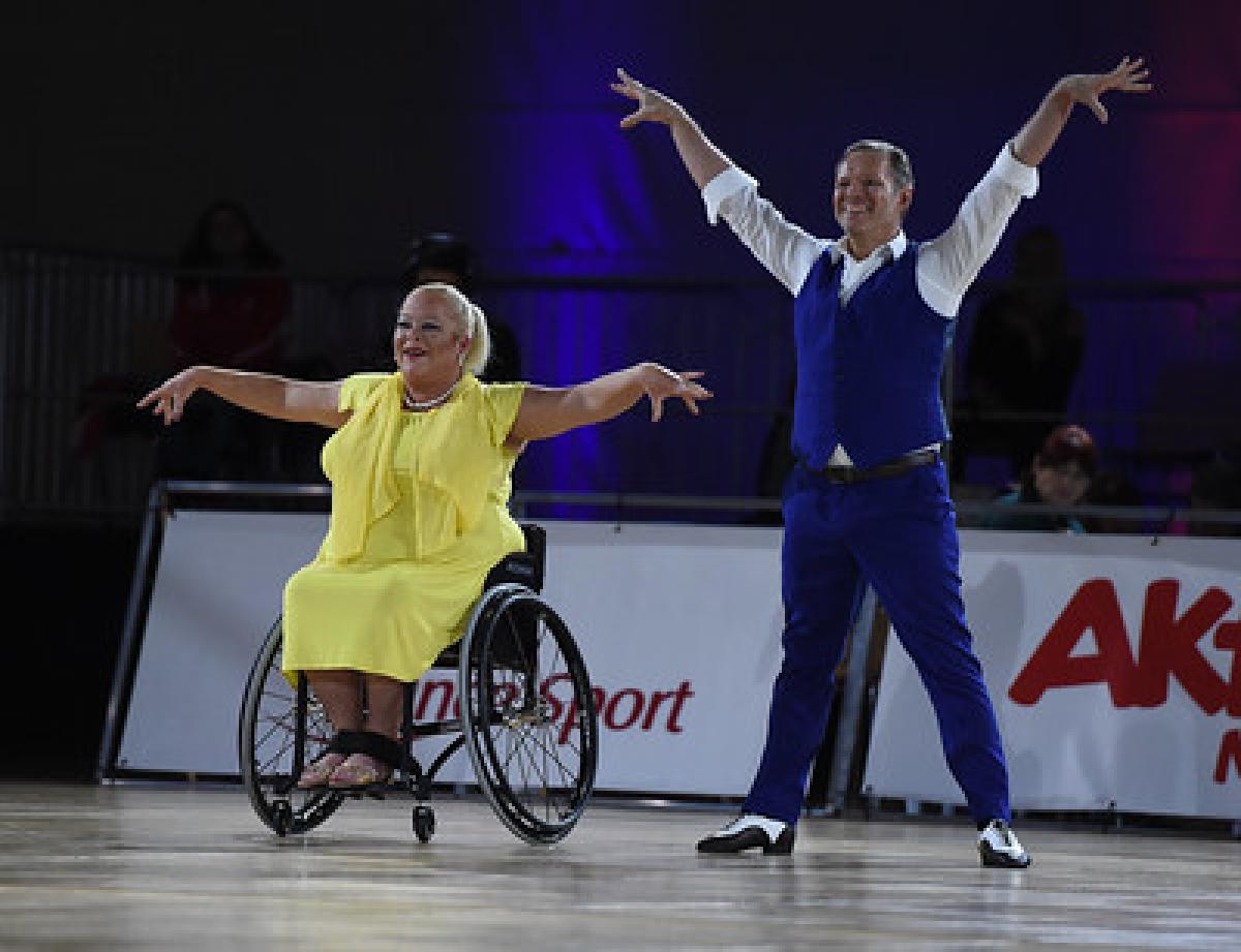 A female wheelchair dancer next to her standing male dance partner