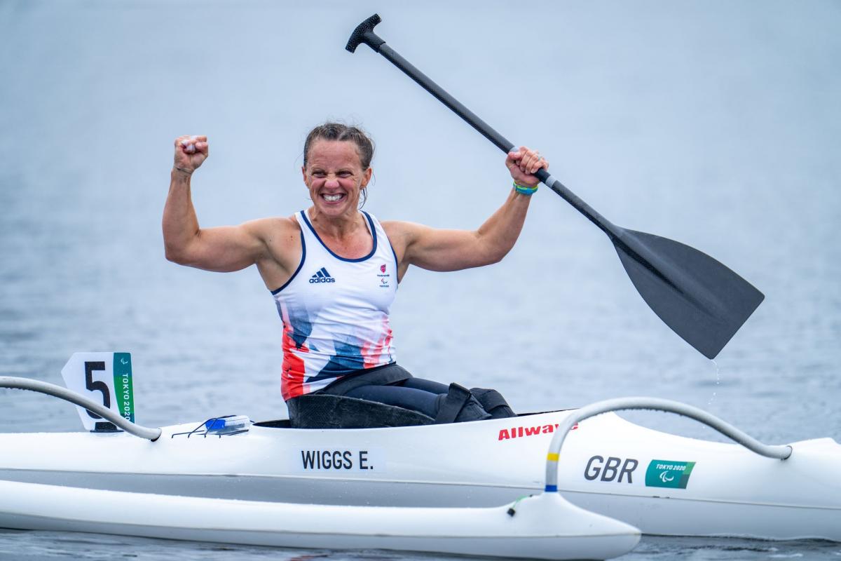 A female Para canoe athlete celebrates on her boat after winning her race at Tokyo 2020.