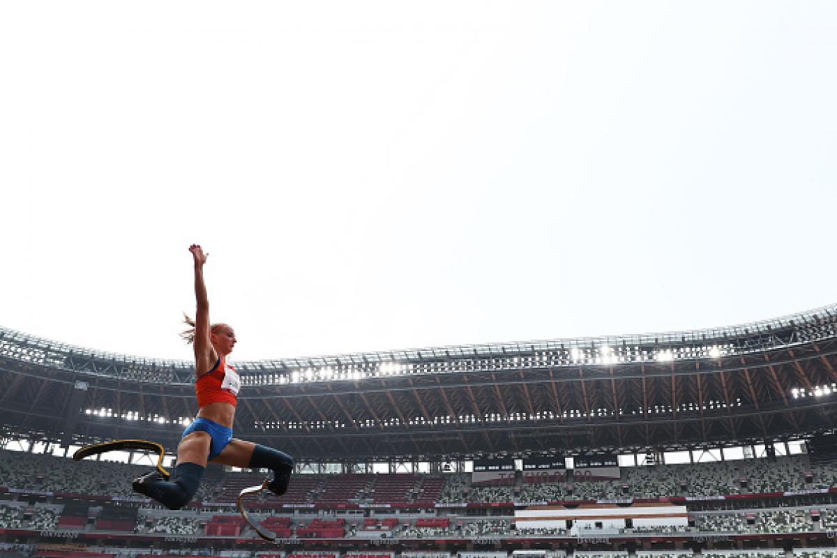 A female athlete with prosthetic legs jumping in an empty stadium