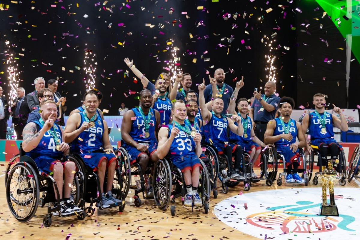 About 20 wheelchair basketball players and officials celebrate after winning the gold medal.