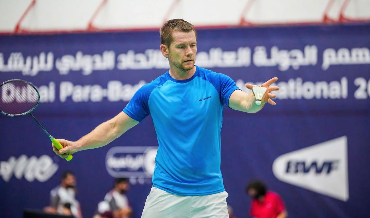 A male athlete serving in a badminton match