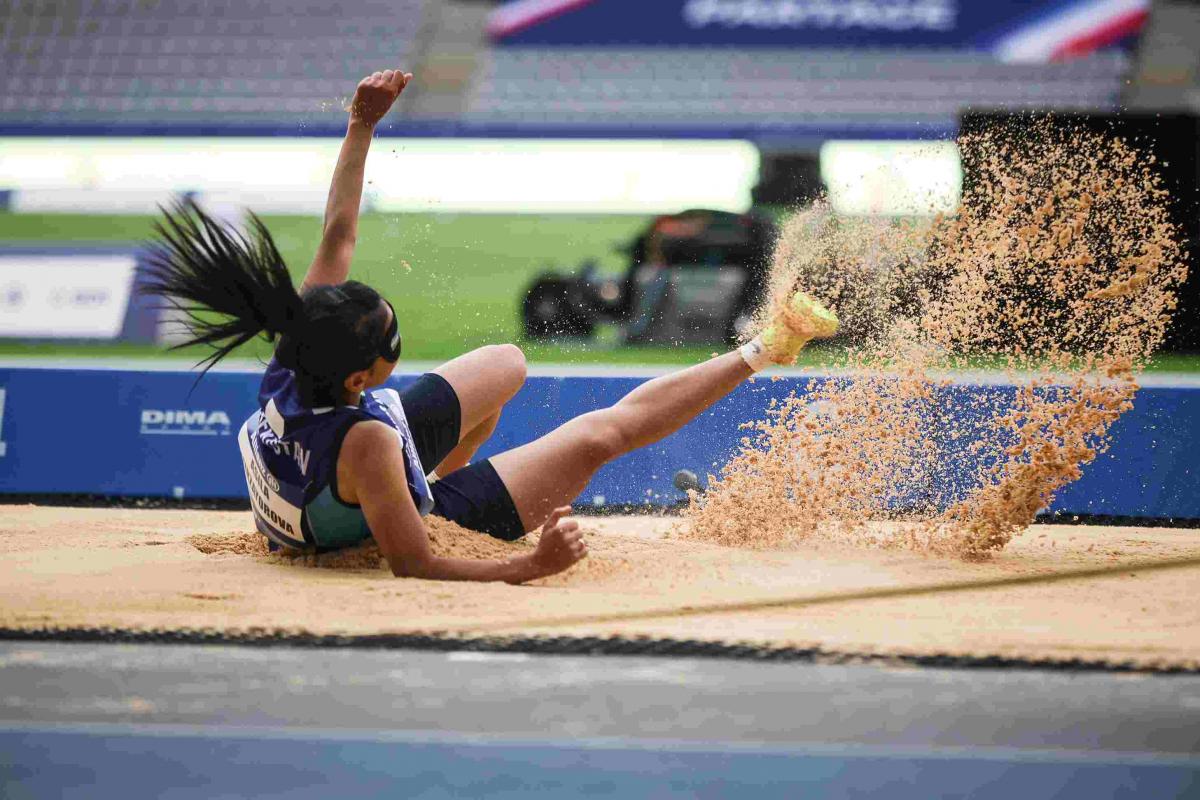 A female long jumper landing on a sand box