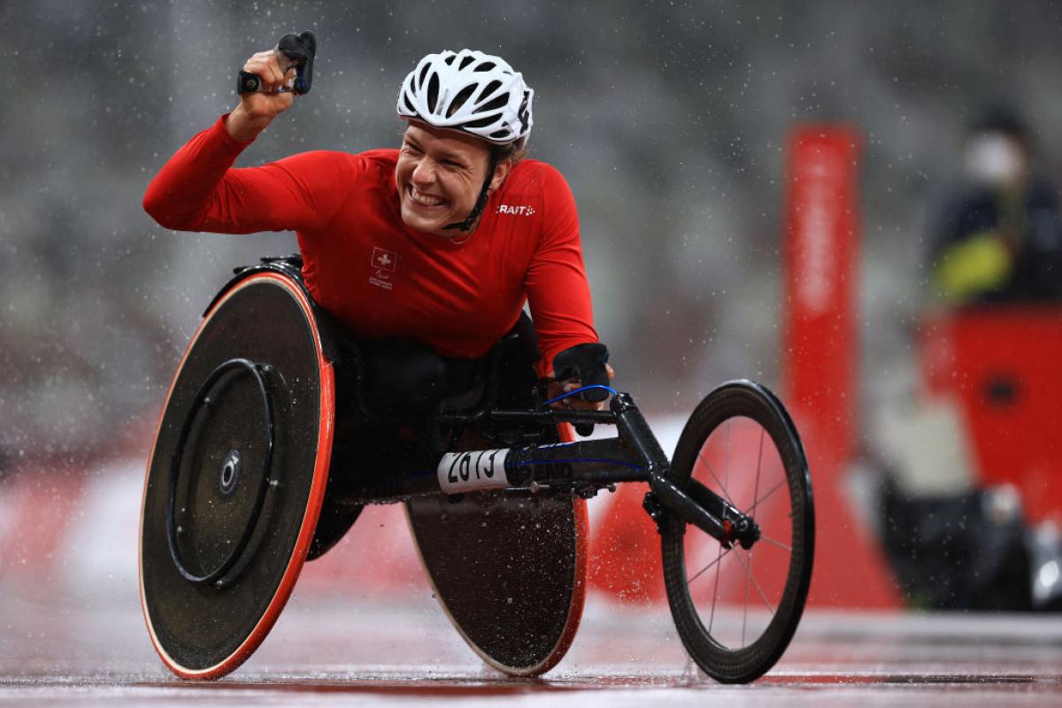 Wheelchair racer Catherine Debrunner celebrates winning with her fist raised in the air