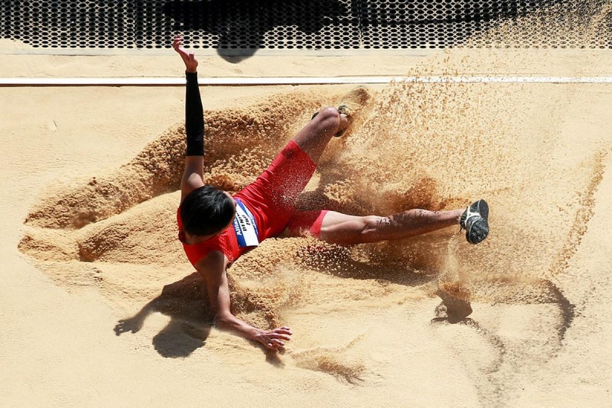 A man landing in the sand pit in a long jump event
