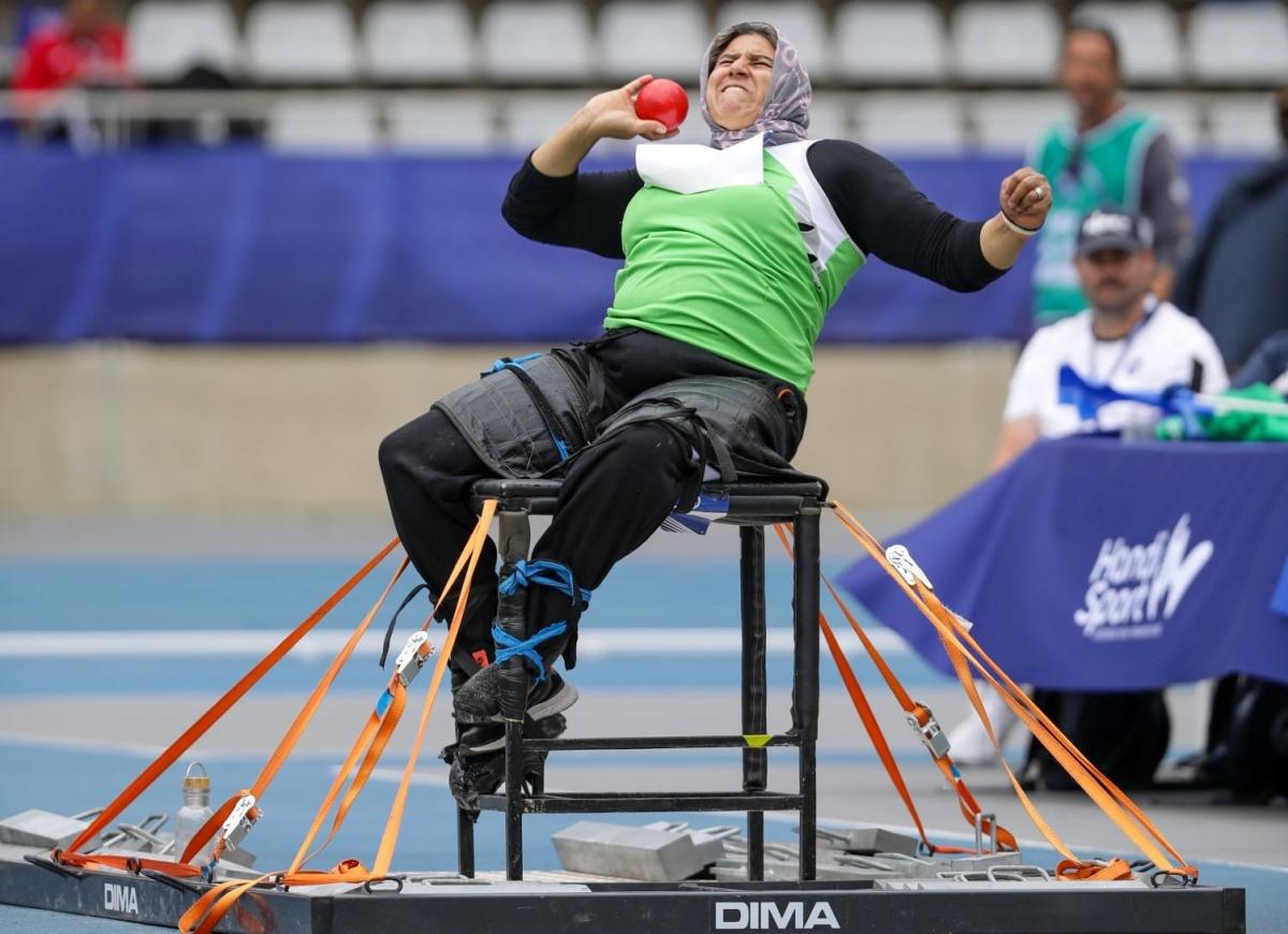 A female athlete competing in the shot put