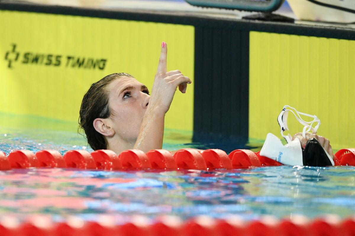 A female swimmer in the water pointing to the sky 