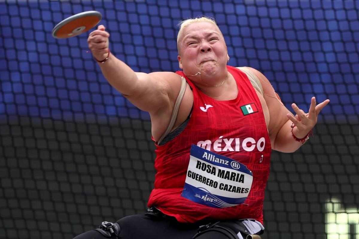 A female seated athlete throws a discus 