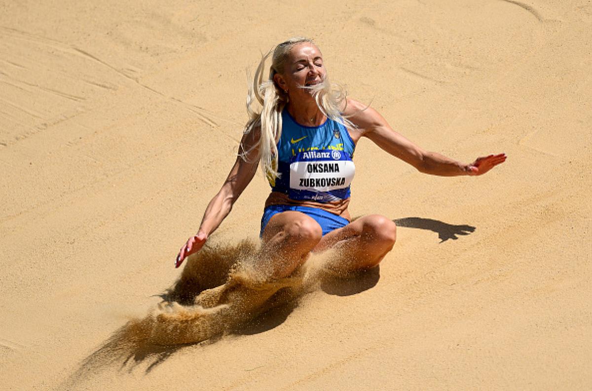 A female long jumper landing on the sand box