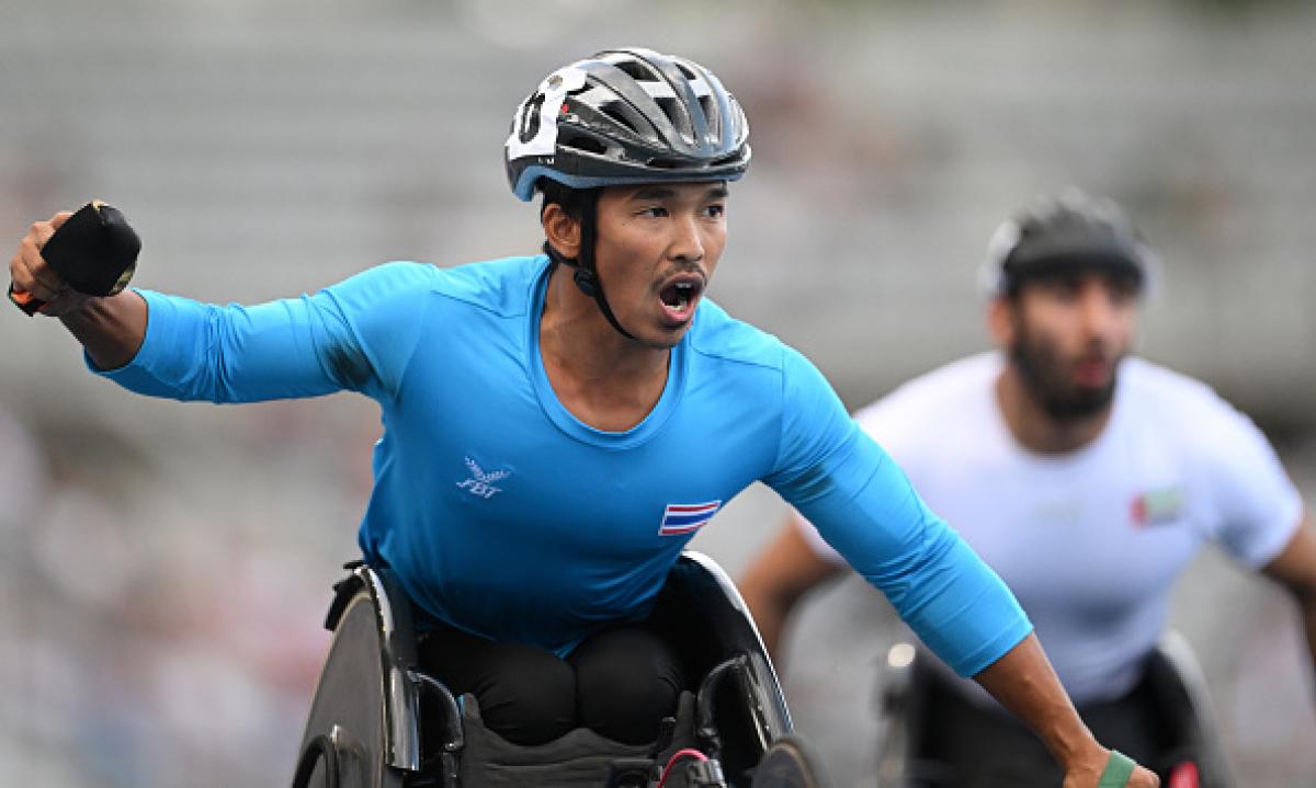 A man in a racing wheelchair celebrating 