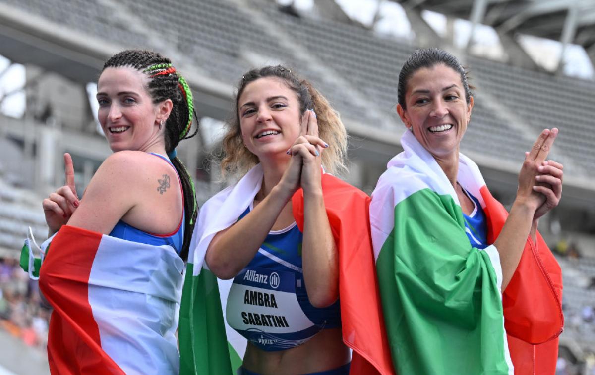 Martina Caironi, Ambra Sabatini, Monica Graziana posing together wrapped in the Italian flag