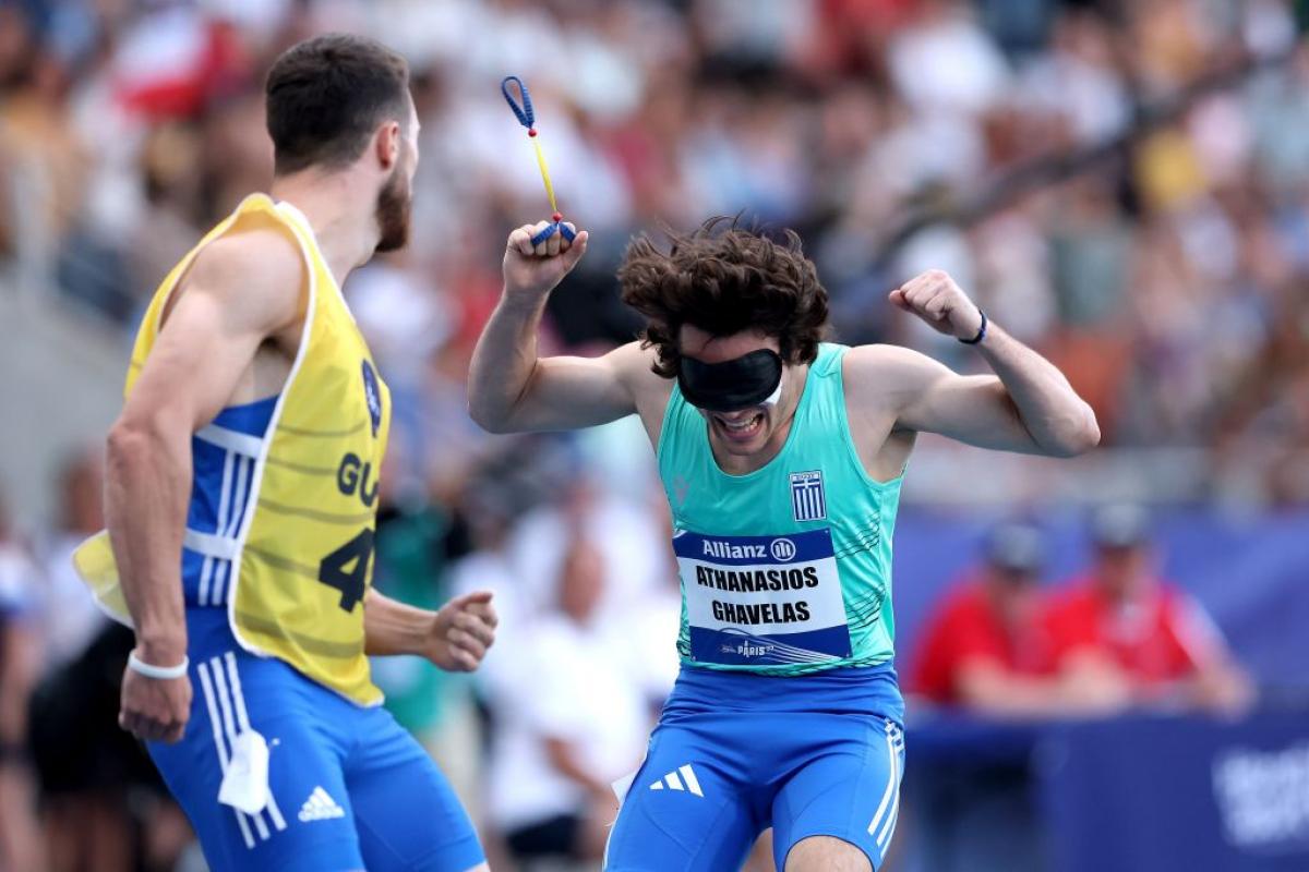 A blindfolded athlete celebrating near an athlete with a guide bib