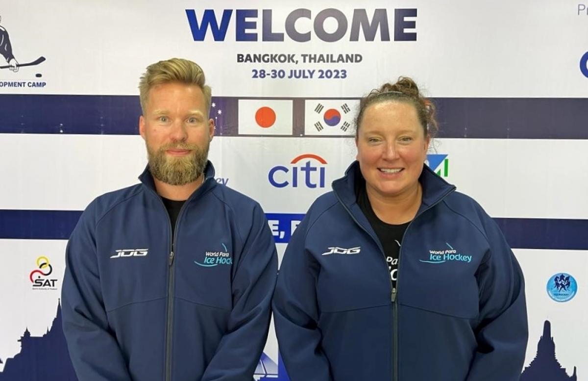 A man and a woman standing in front of a Welcome backdrop 