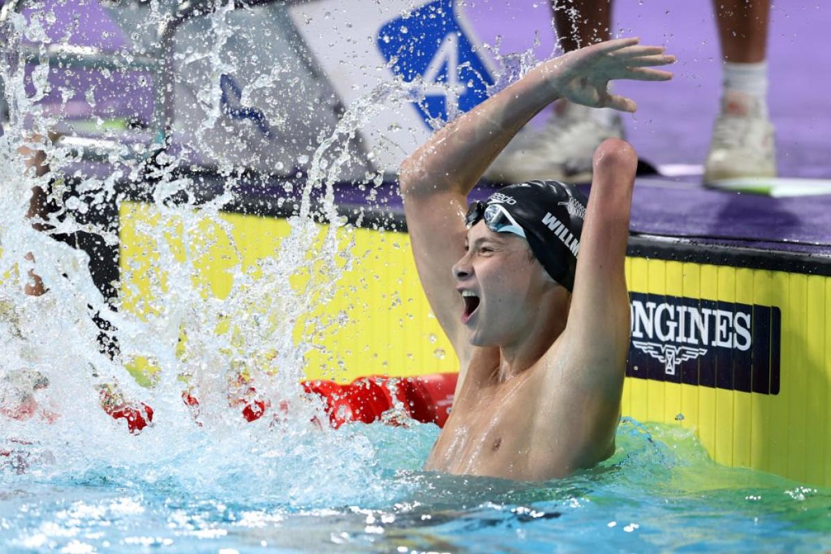 A young armless male swimmer celebrating in the pool