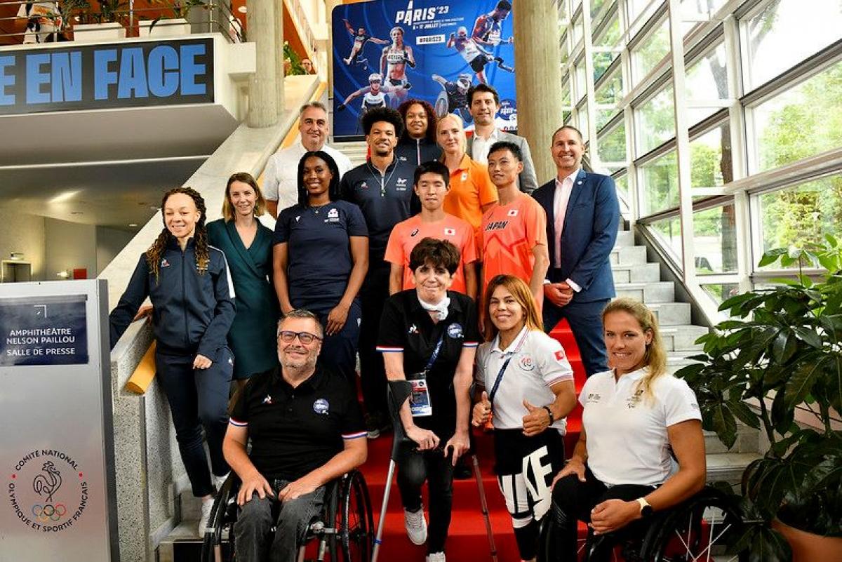 Fifteen athletes and officials pose for a photograph 