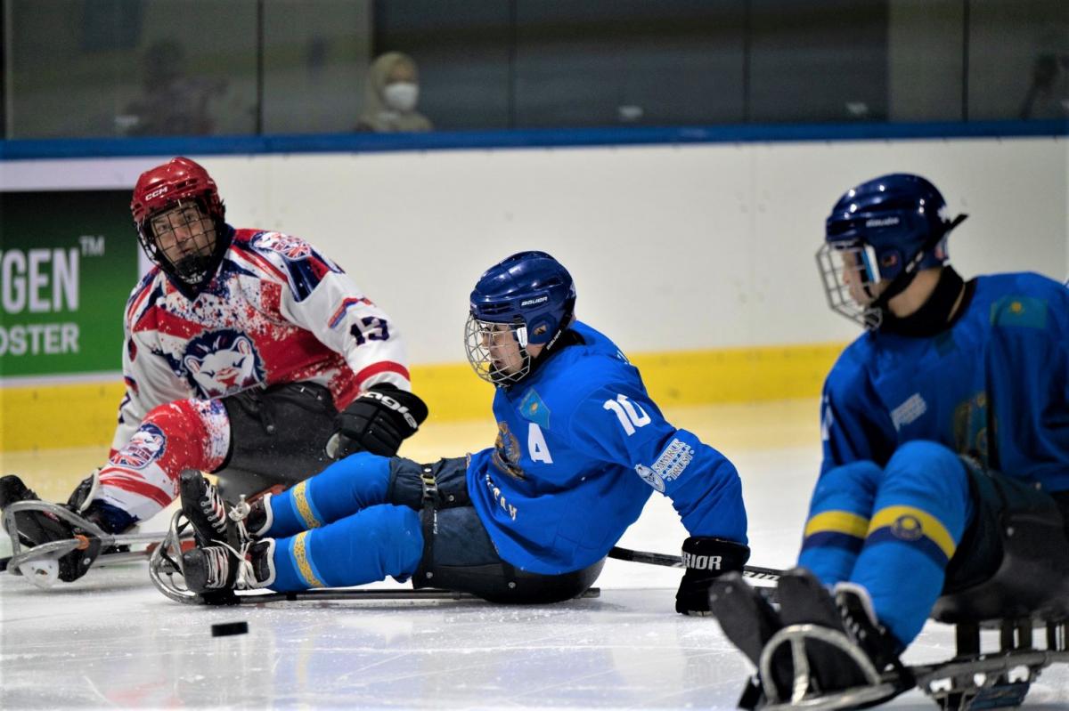 A Para ice hockey player trying a pass in front of other two players
