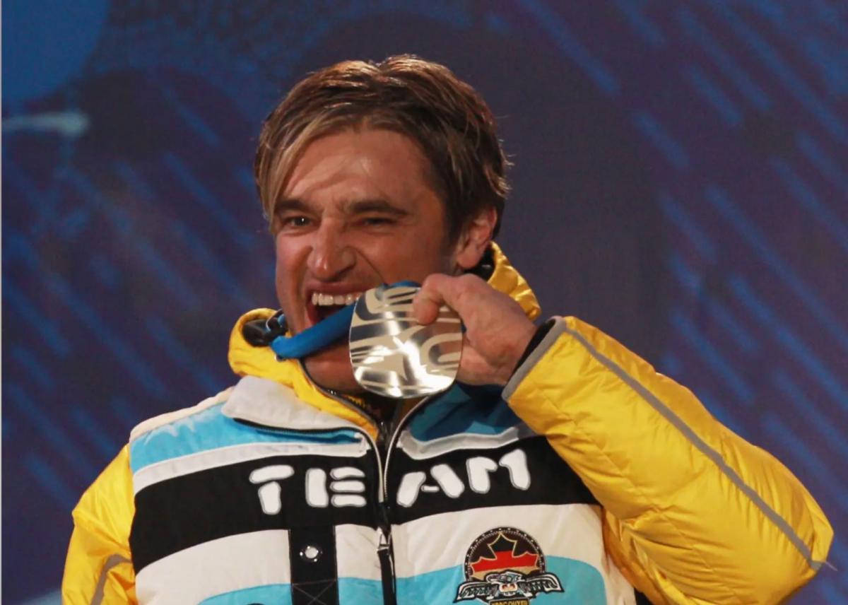 A picture of a man beating his silver medal during a medal ceremony