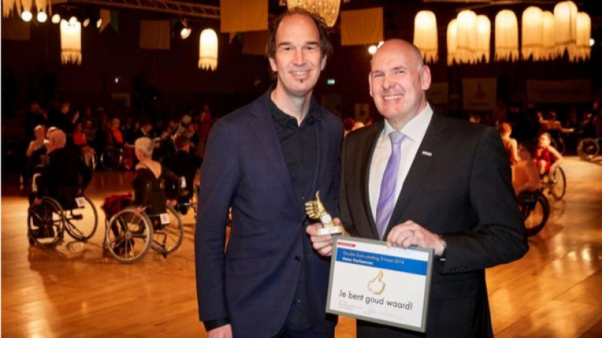 A man smiling with a small trophy next to another man