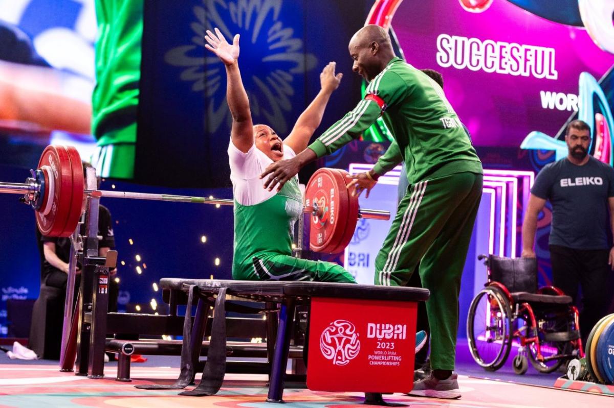 A female powerlifter celebrating with her male coach