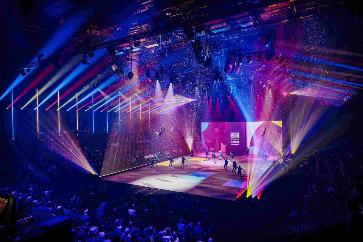 dancers performing on a stage surrounded by brightly coloured light beams