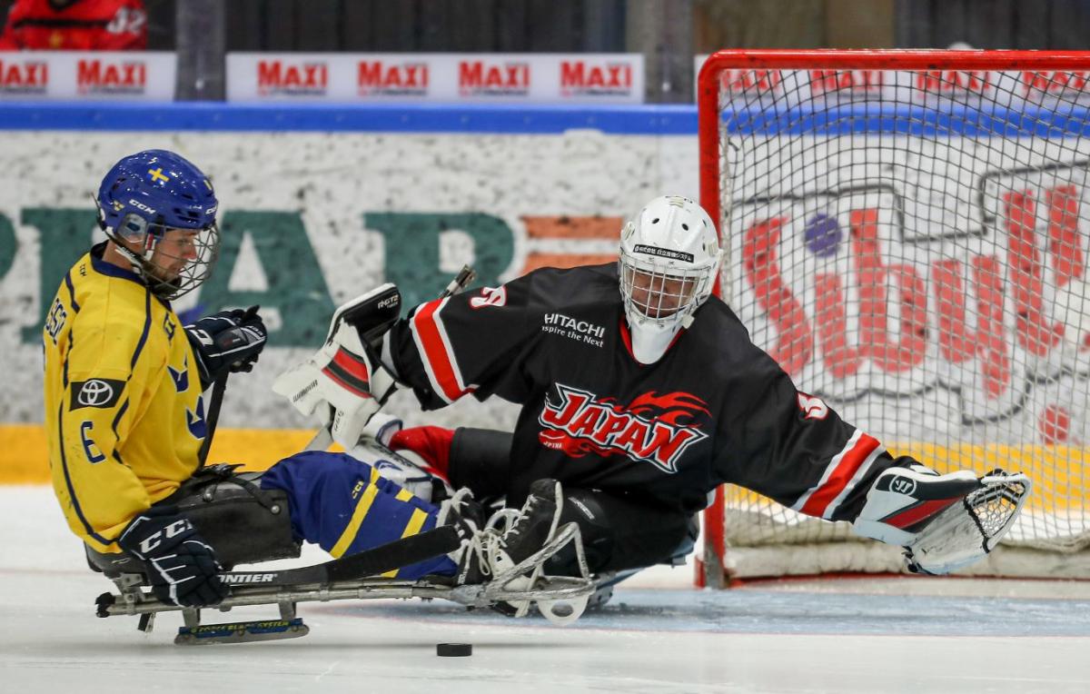 A Para ice hockey player taking a shot in front of the goaltender