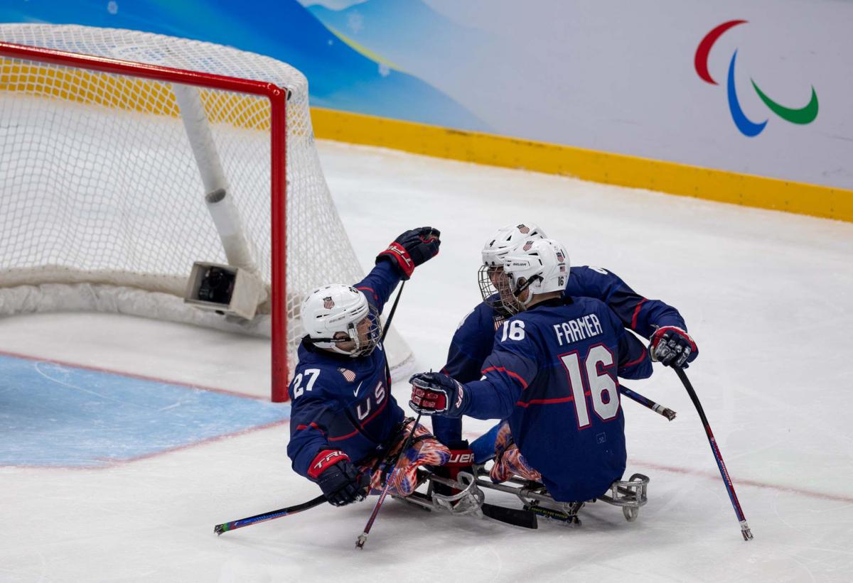 Three USA Para ice hockey players celebrating a goal