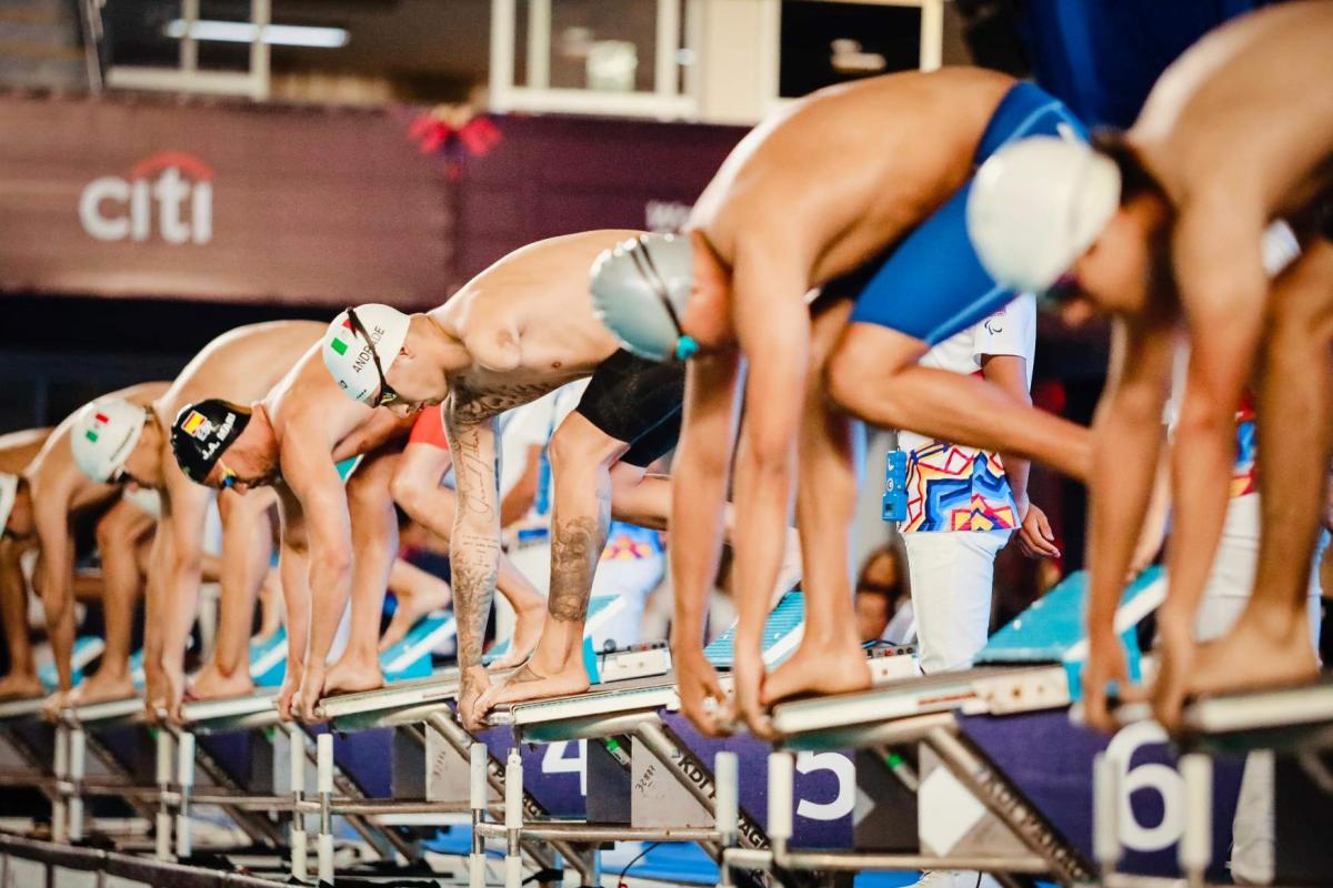 Six men on starting blocks of a Para swimming race