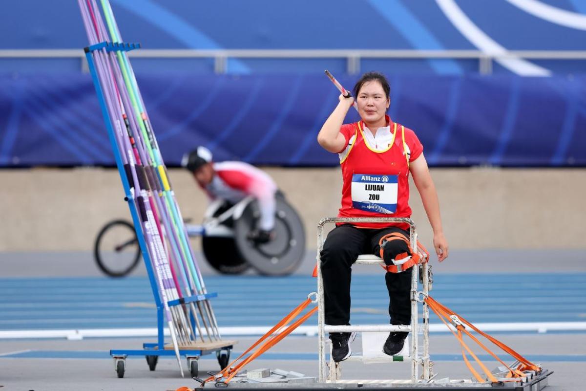 A female seated javelin thrower in a Para athletics competition