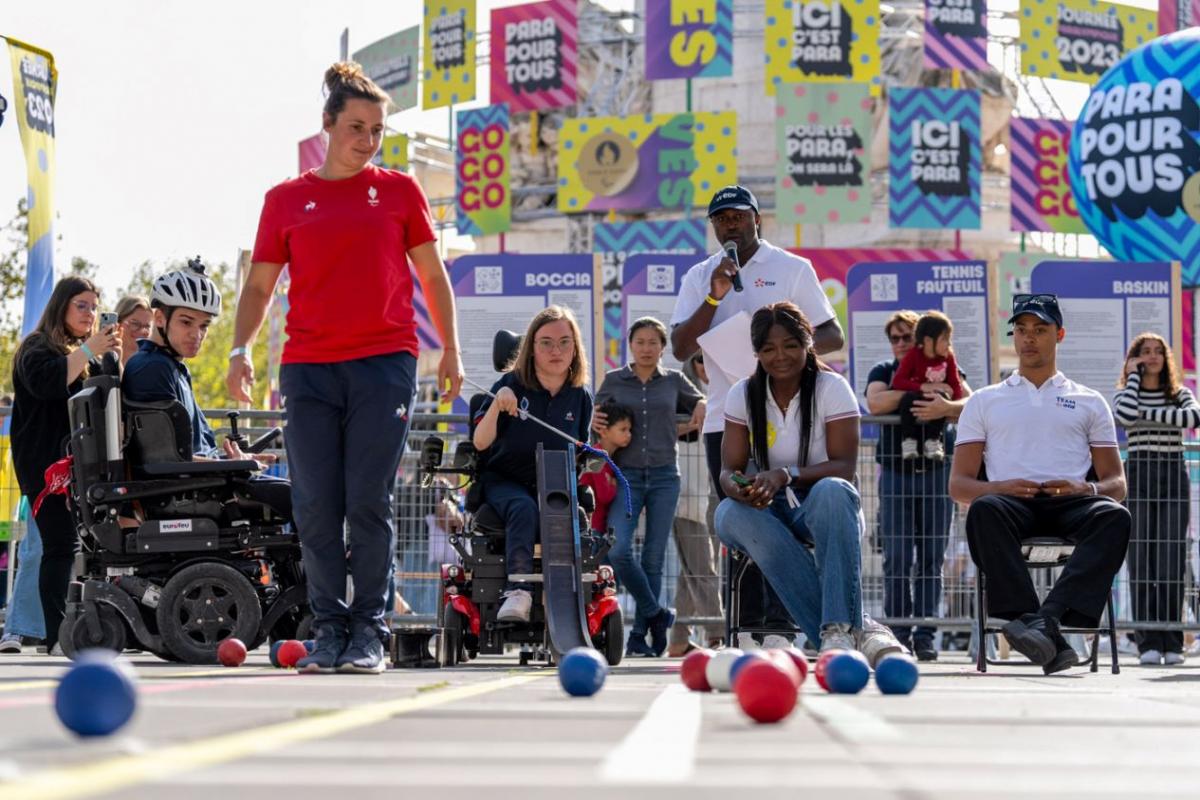 People demonstrate playing boccia in front of a crowd