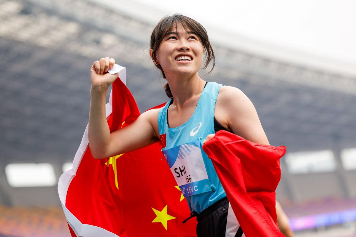A female athlete with a Chinese flag in a athletics stadium