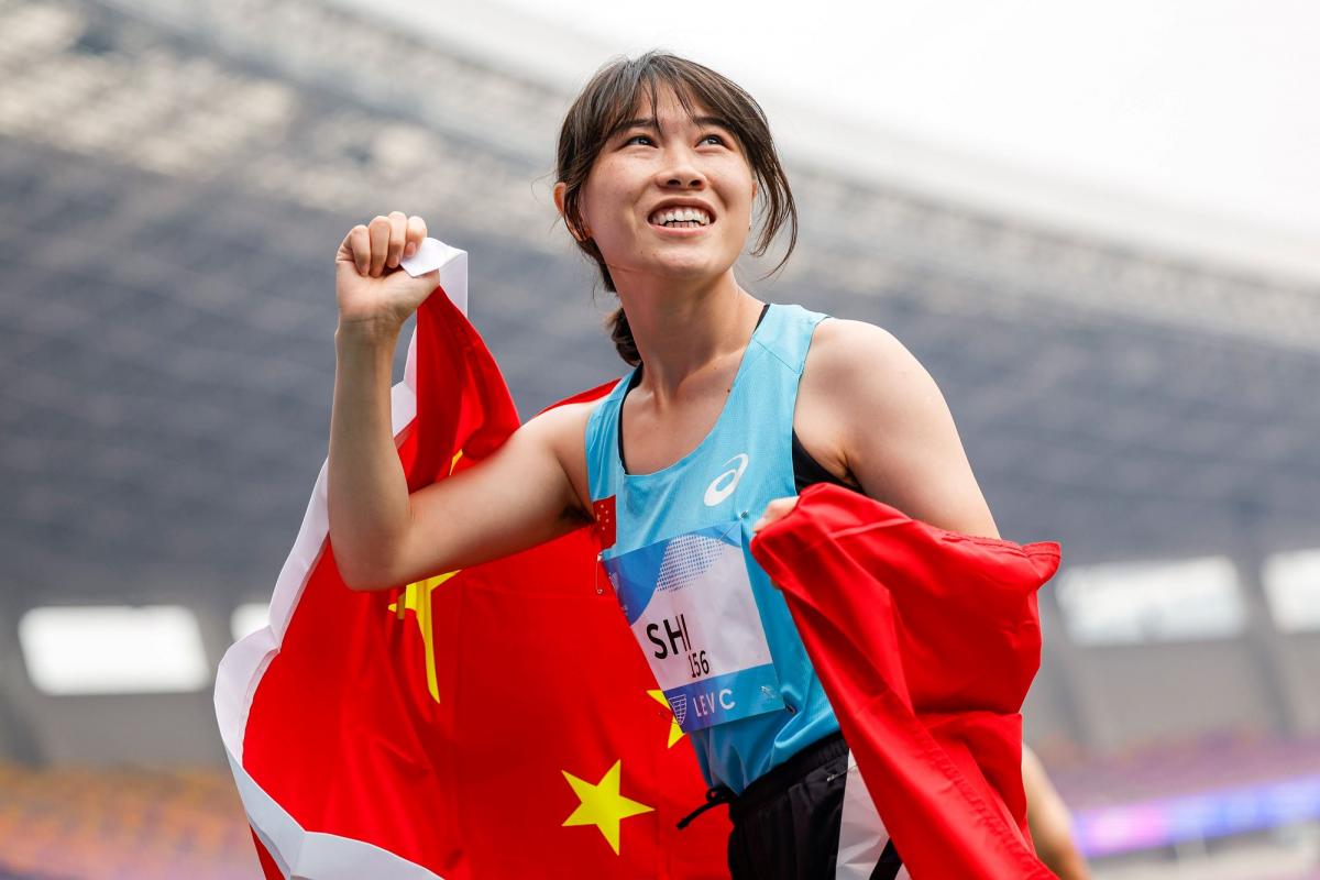 A female athlete with a Chinese flag in a athletics stadium