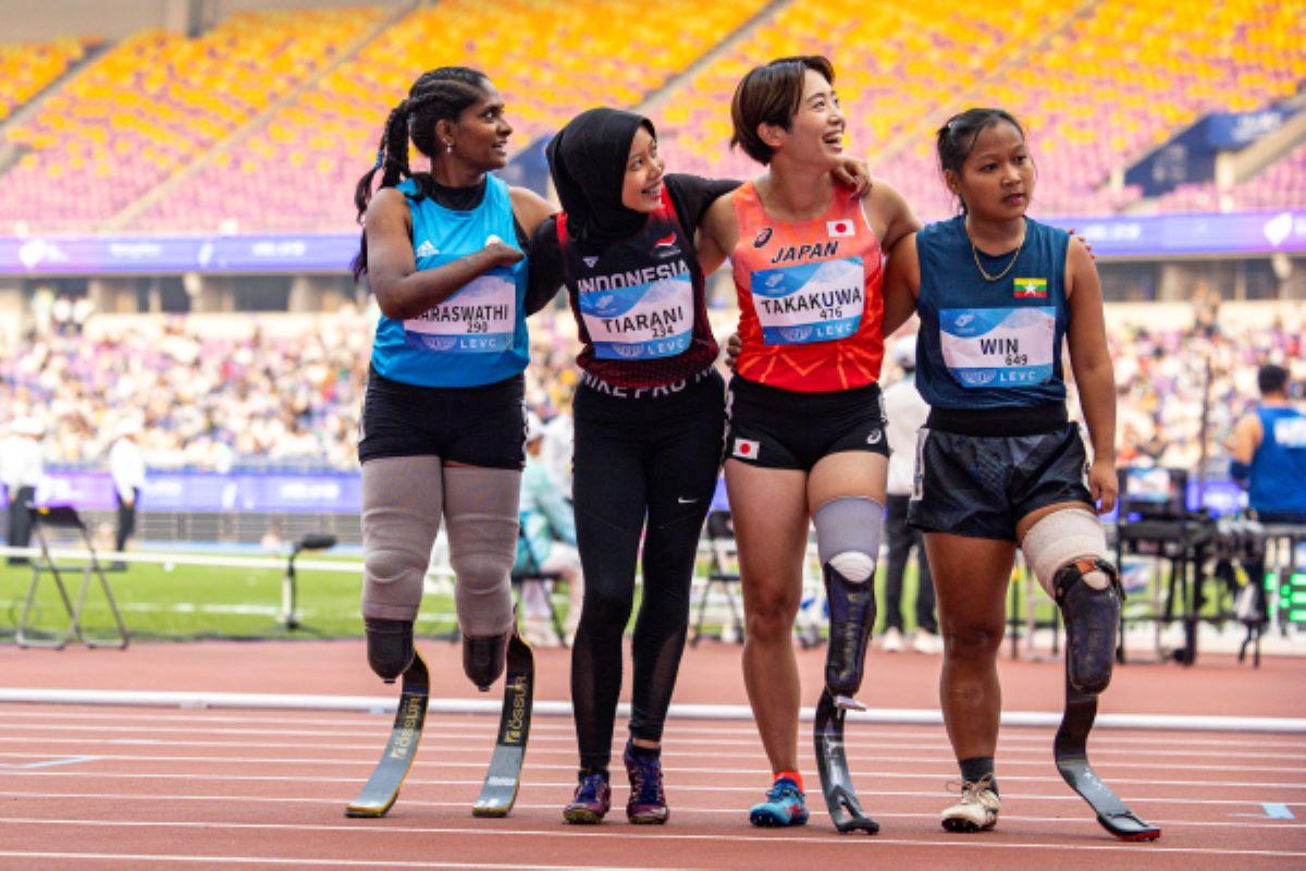 Four female athletes with running blades look to their left side