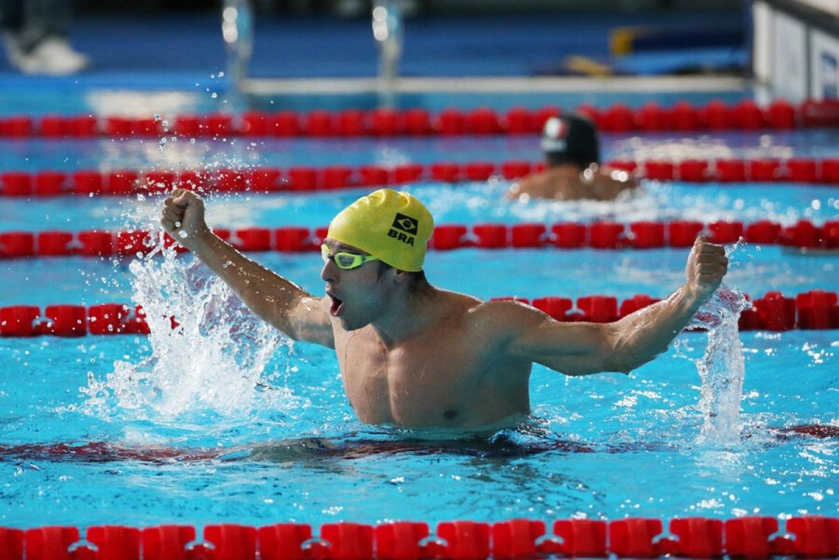 A male swimmer with a cap of Brazil celebrating in the pool