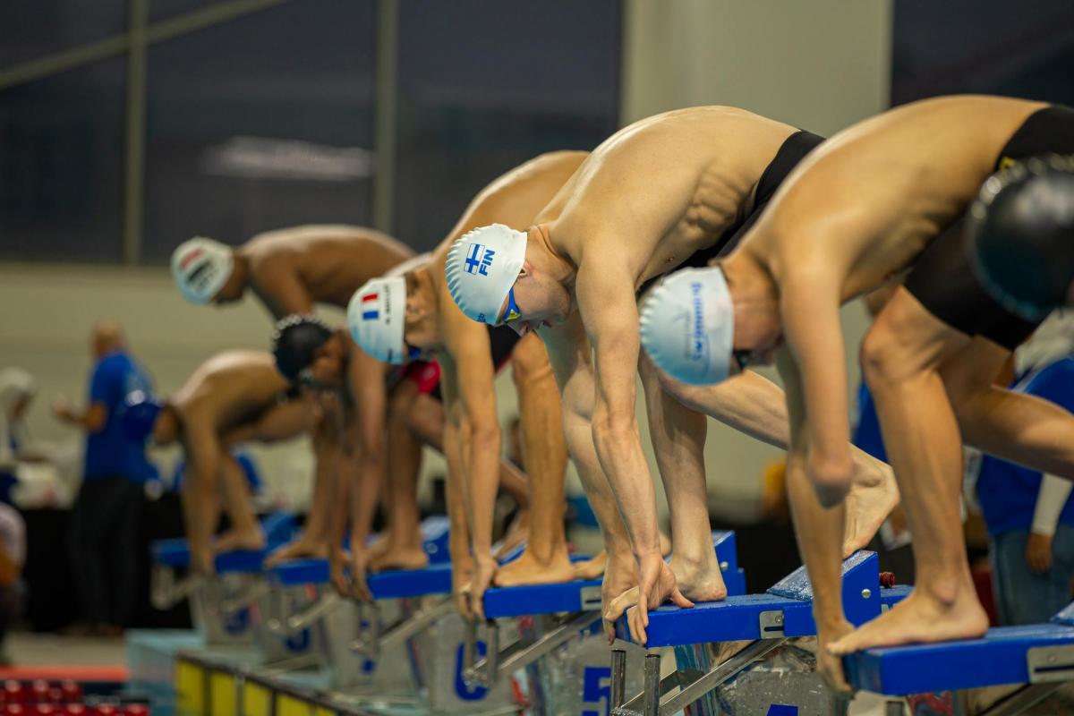 Seven Para swimmers on the starting block before a race