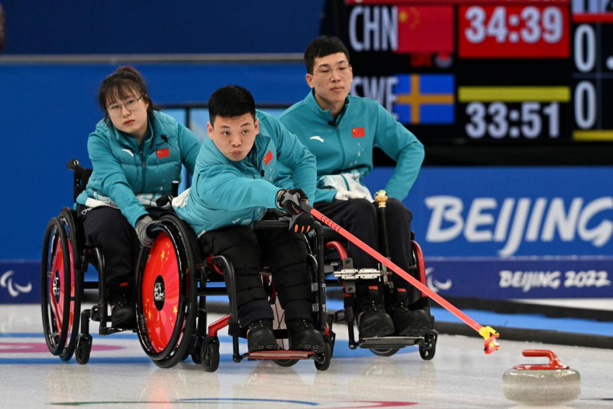 Three wheelchair curling athletes on the ice at Beijing 2022