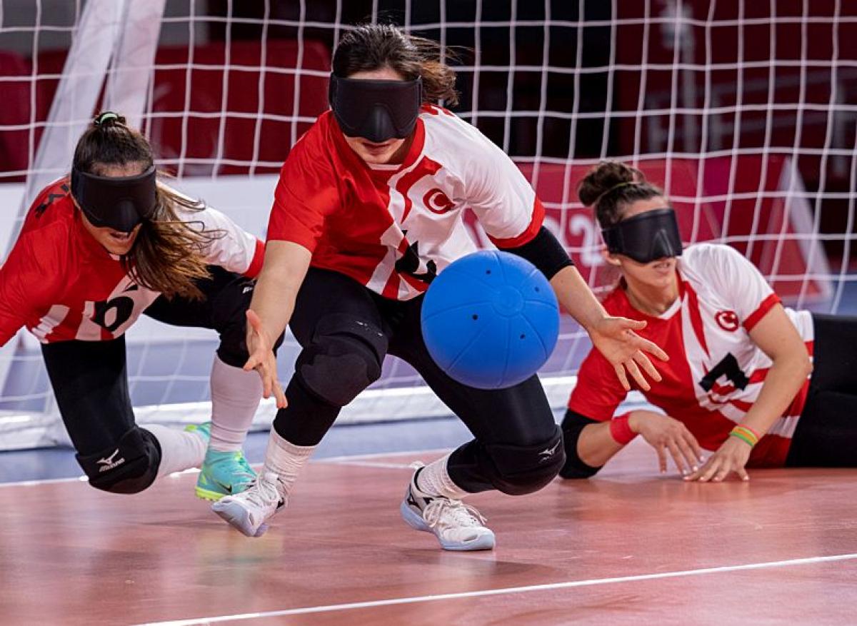 Three female players wearing eyeshades compete in goalball