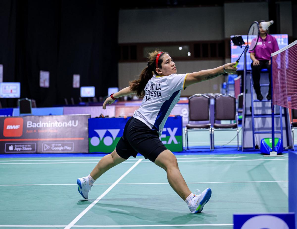 A female Para badminton player reaches for the shuttle during a Para badminton match