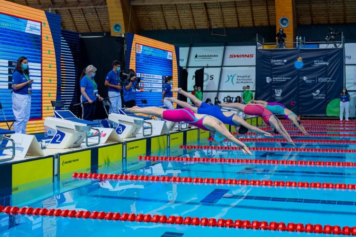 Four female Para swimmers jump in the water