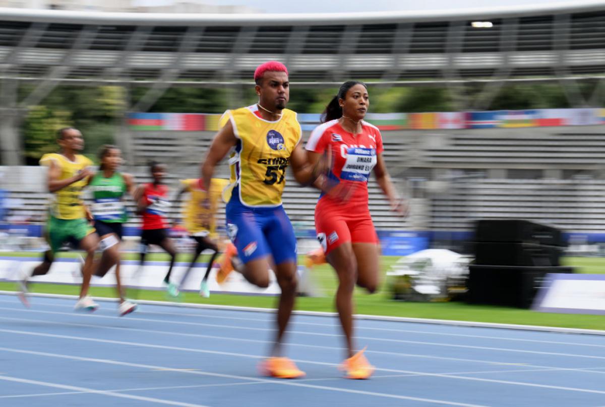 A female sprinter and her male guide race. They are in front of a pack of athletes.
