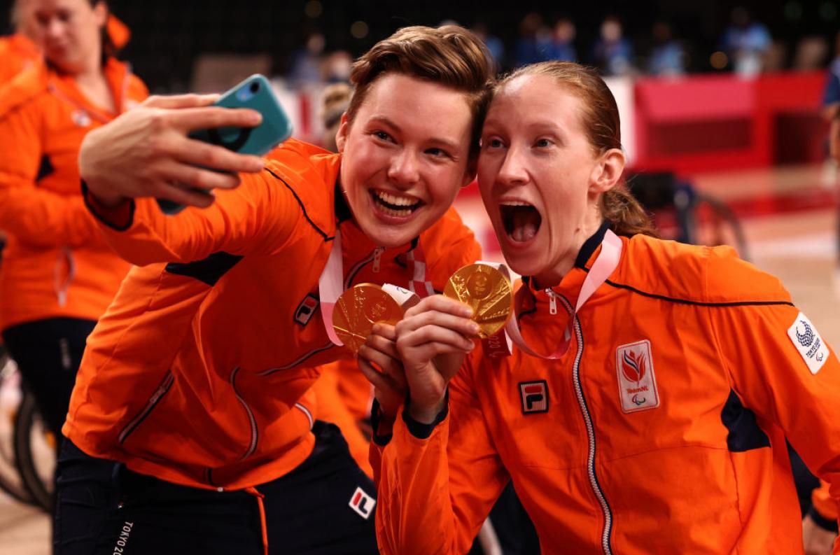 Two Dutch women's wheelchair basketball players take a selfie with their gold medals.