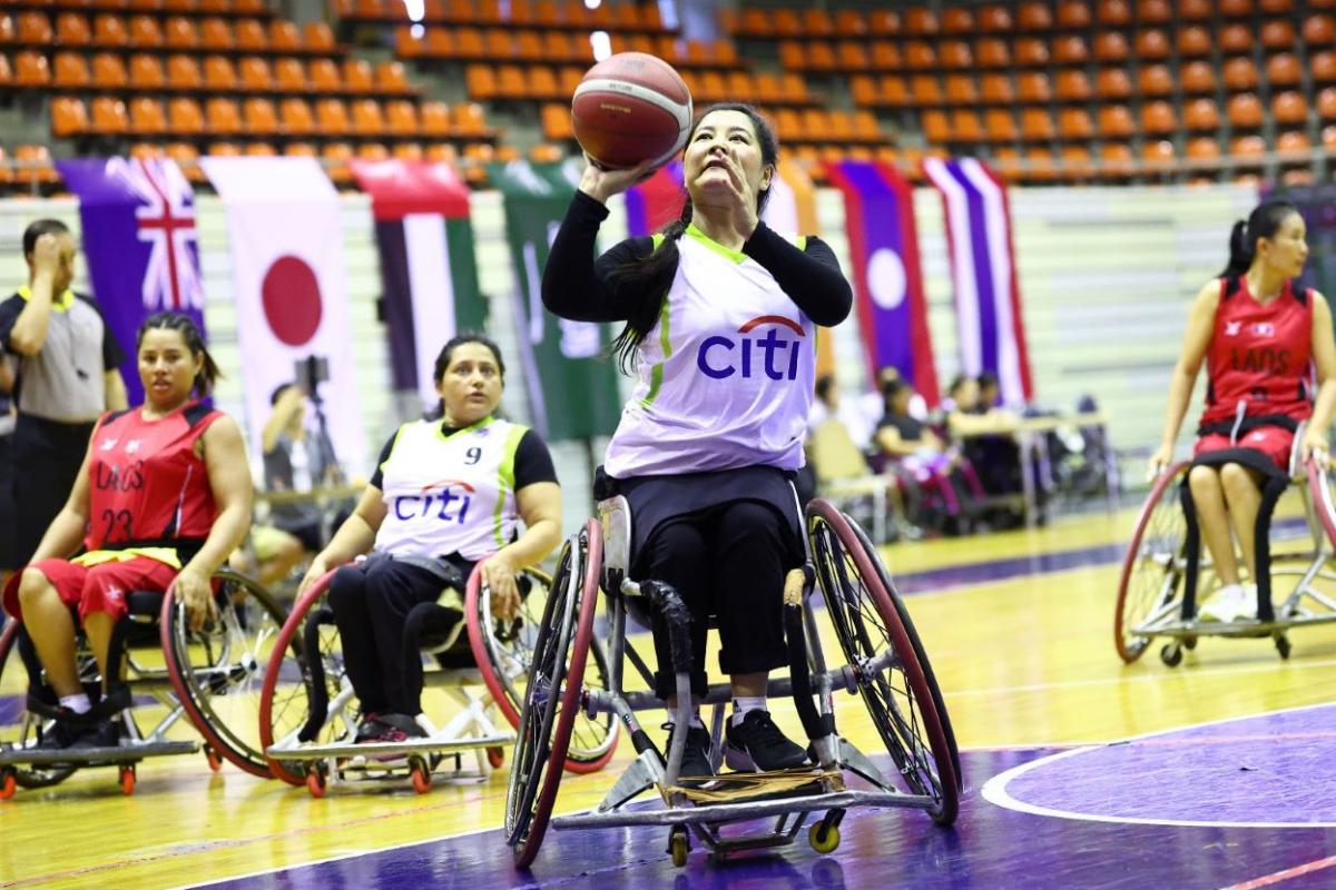A female wheelchair basketball player is about to throw the ball during a match.