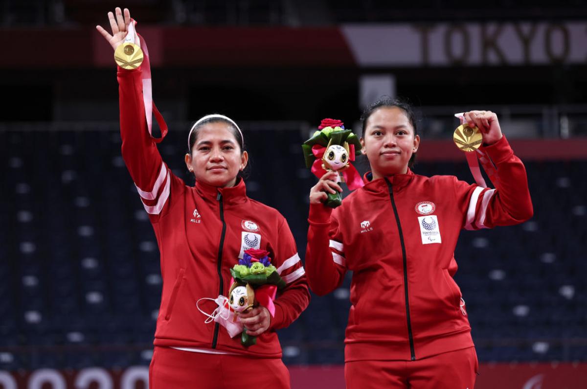 Leani Ratri Oktila and badminton partners raise their medals on the podium