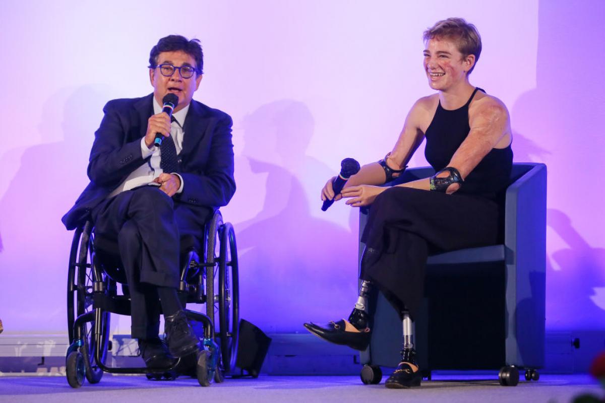 A male official and a female Paralympic athlete are speaking during a conference.