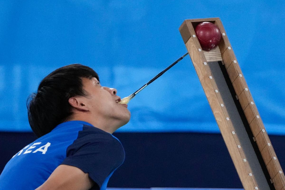 A Korean boccia player uses a a pointer with his mouth to position the ball on the ramp