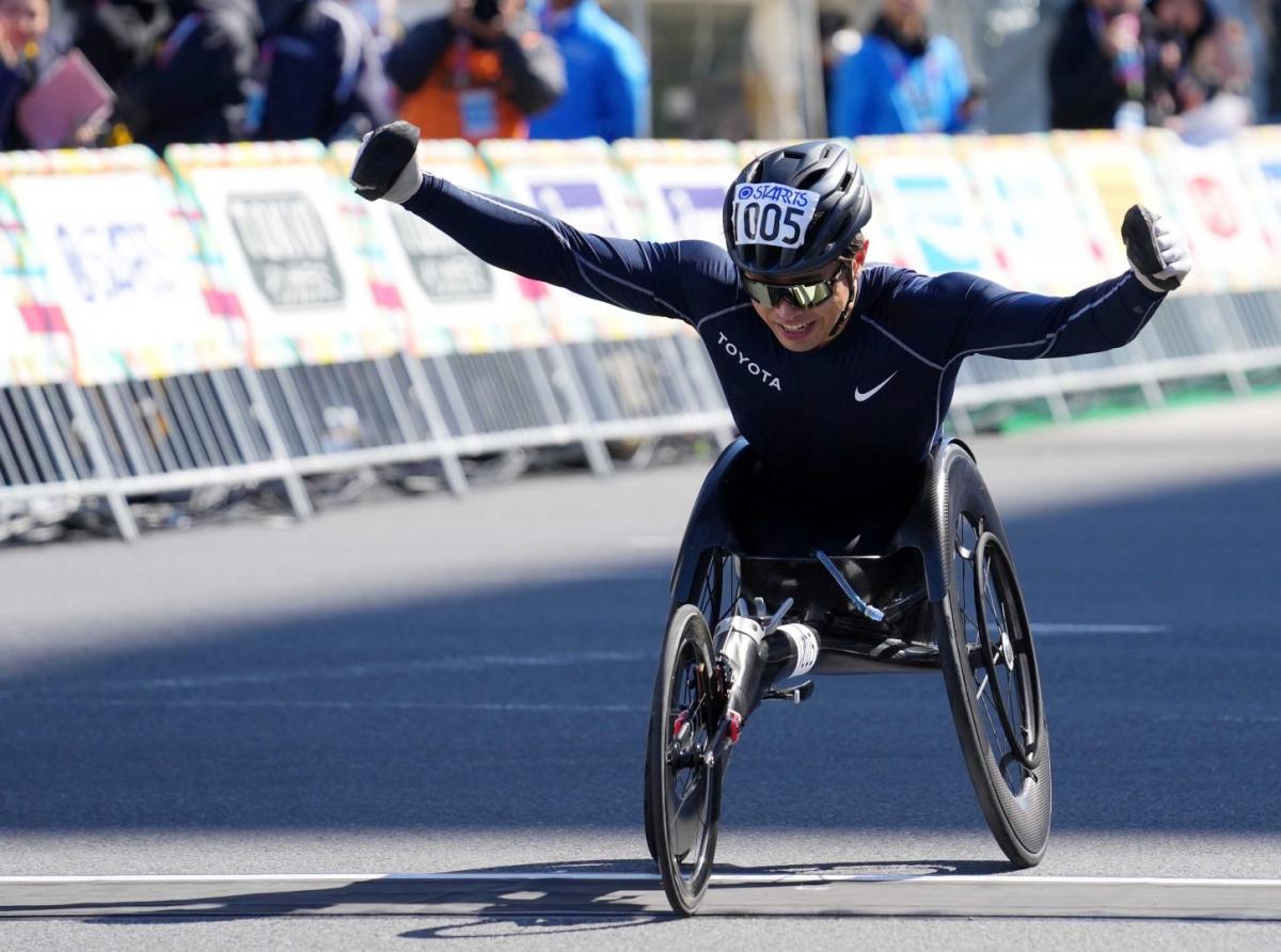 A male wheelchair racer opening his arms in a street marathon