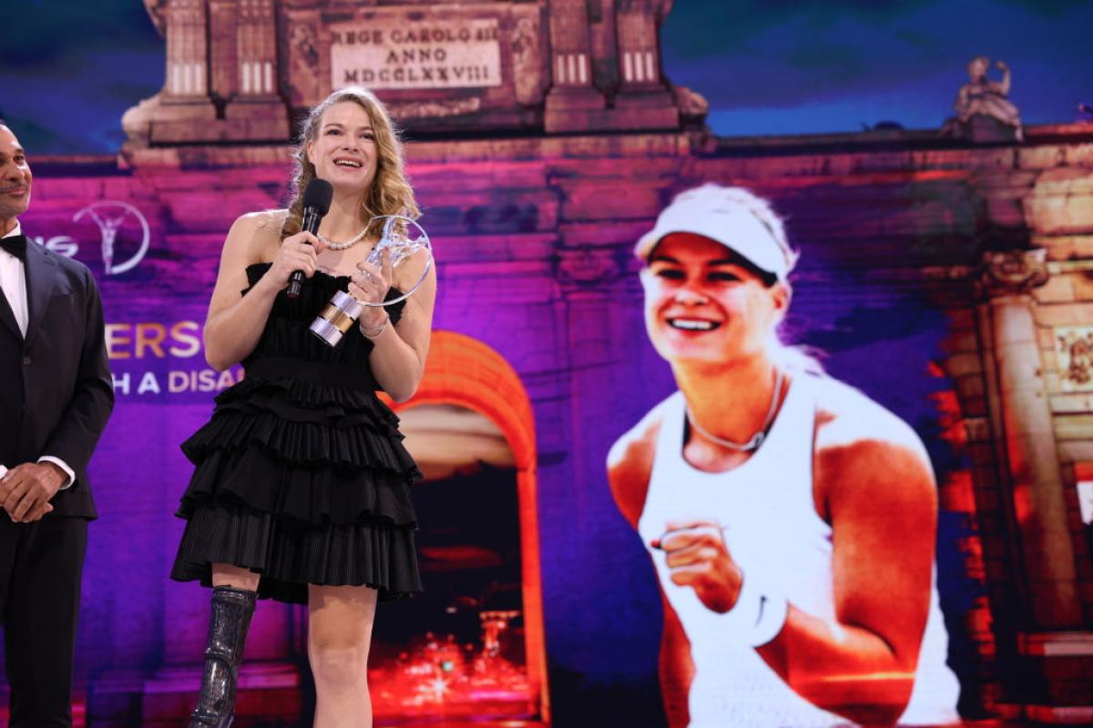 A female athlete makes a speech on a stage.