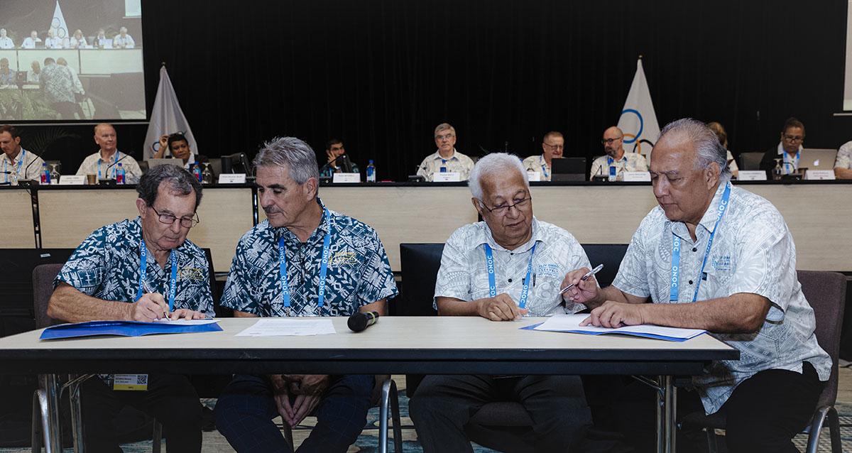 Four male officials sign a document