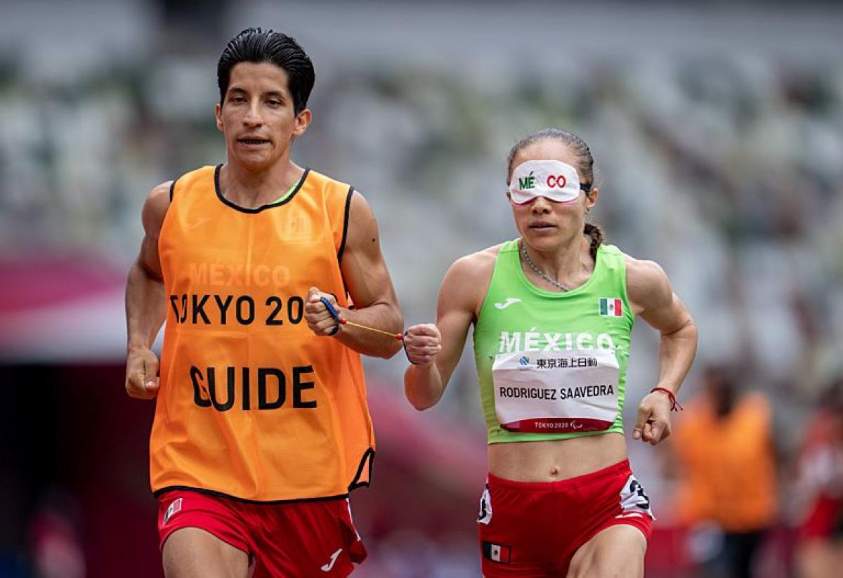 A Para athlete runs with his guide  