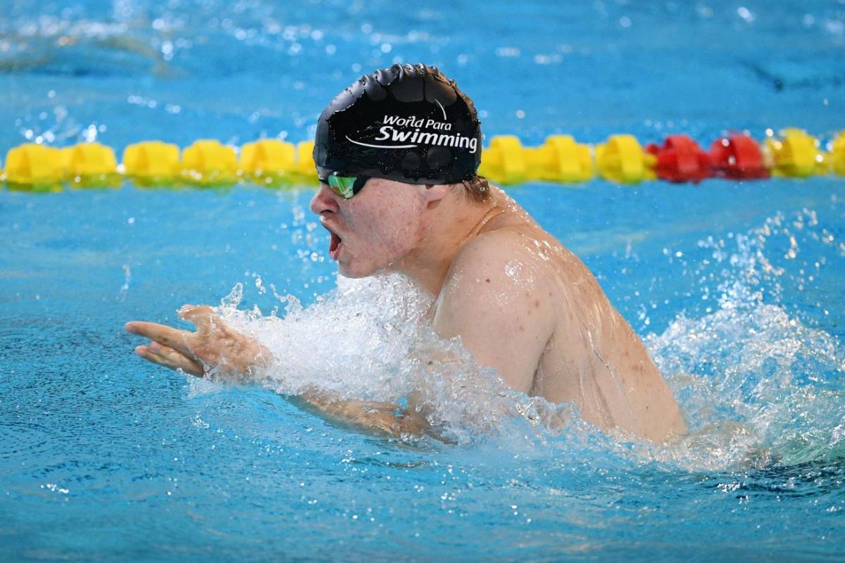 A man with black cap swimming breaststroke 