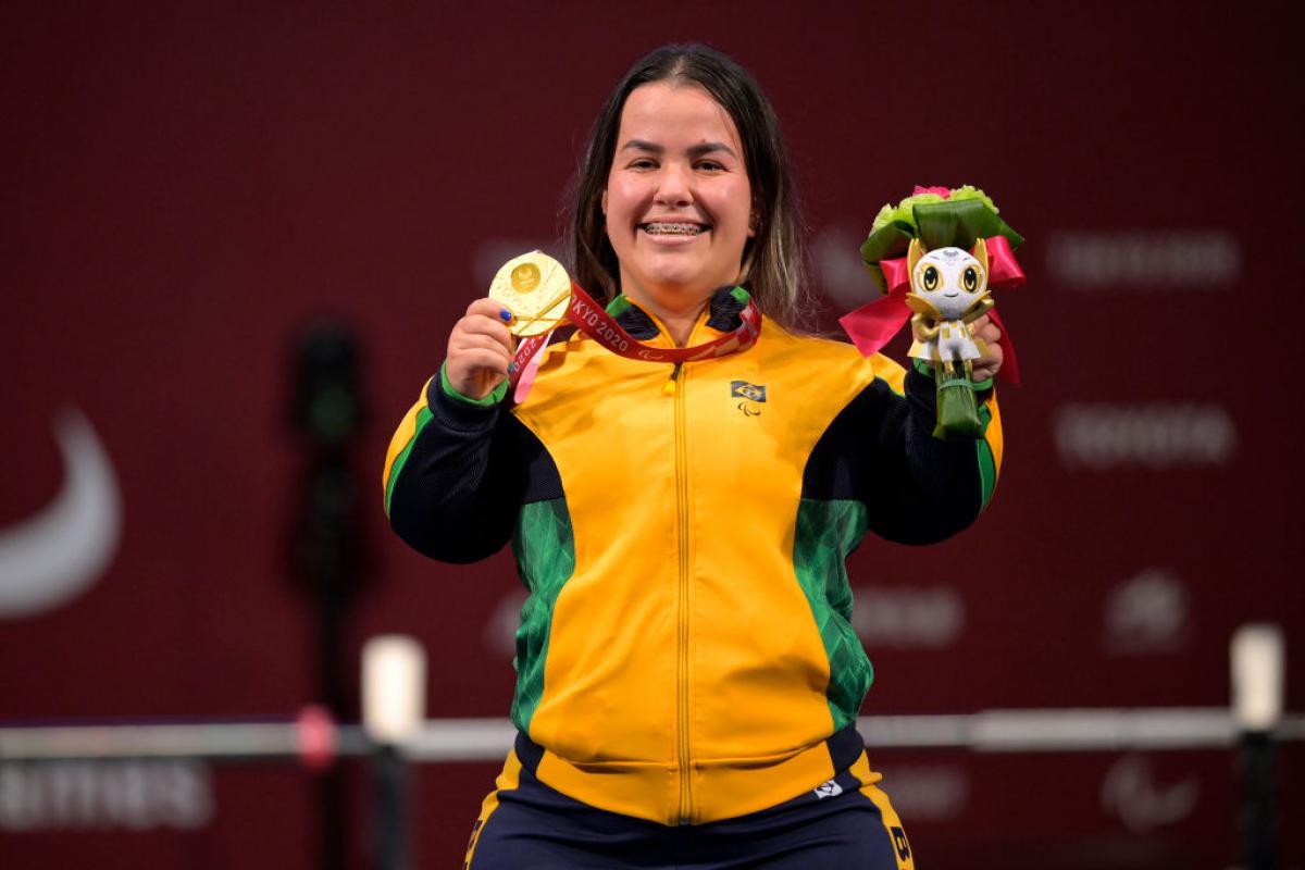 A female Para powerlifter poses for a photo after receiving a gold medal.